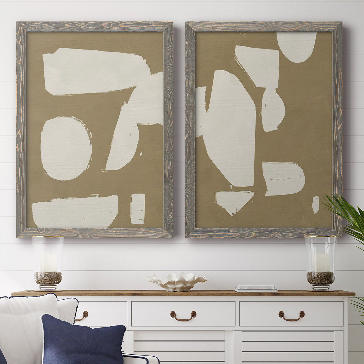 Set of two gray barnwood framed canvas prints depicting a coordinated art pair of irregular white cutout-like shapes on taupe grounds rendered as bold minimalist shape abstracts above a dining room sideboard.