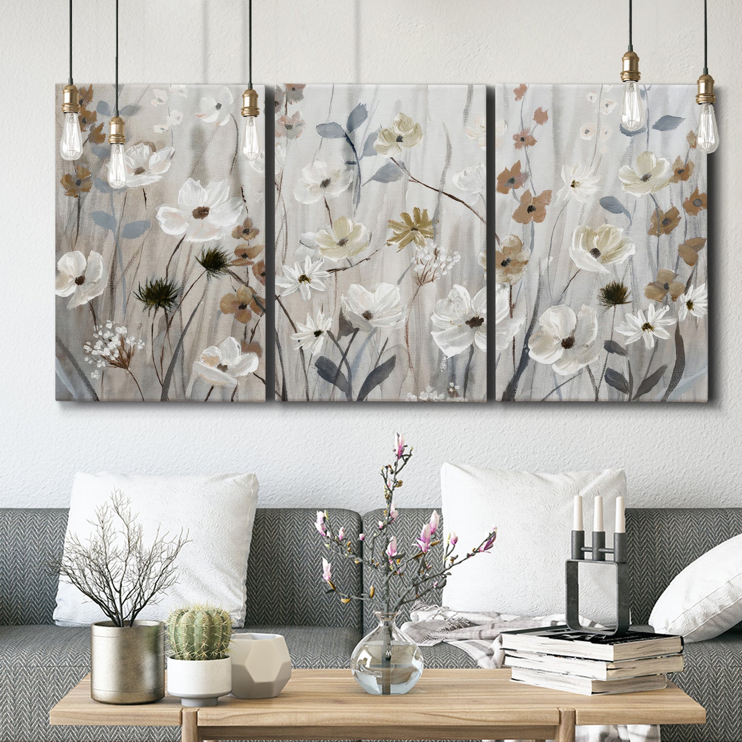 Three-panel canvas wall art featuring misty wildflower meadow landscape, displayed in a modern living room above seating.