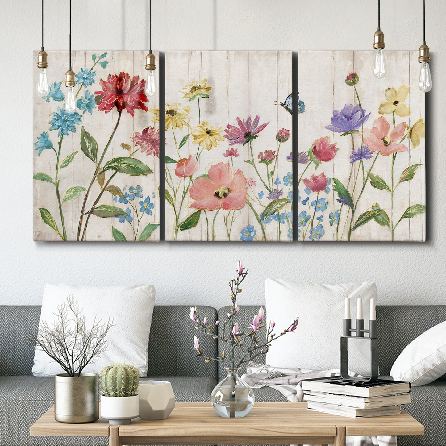 Three-panel canvas wall art featuring delicate wildflower illustration, displayed in a modern living room above seating.