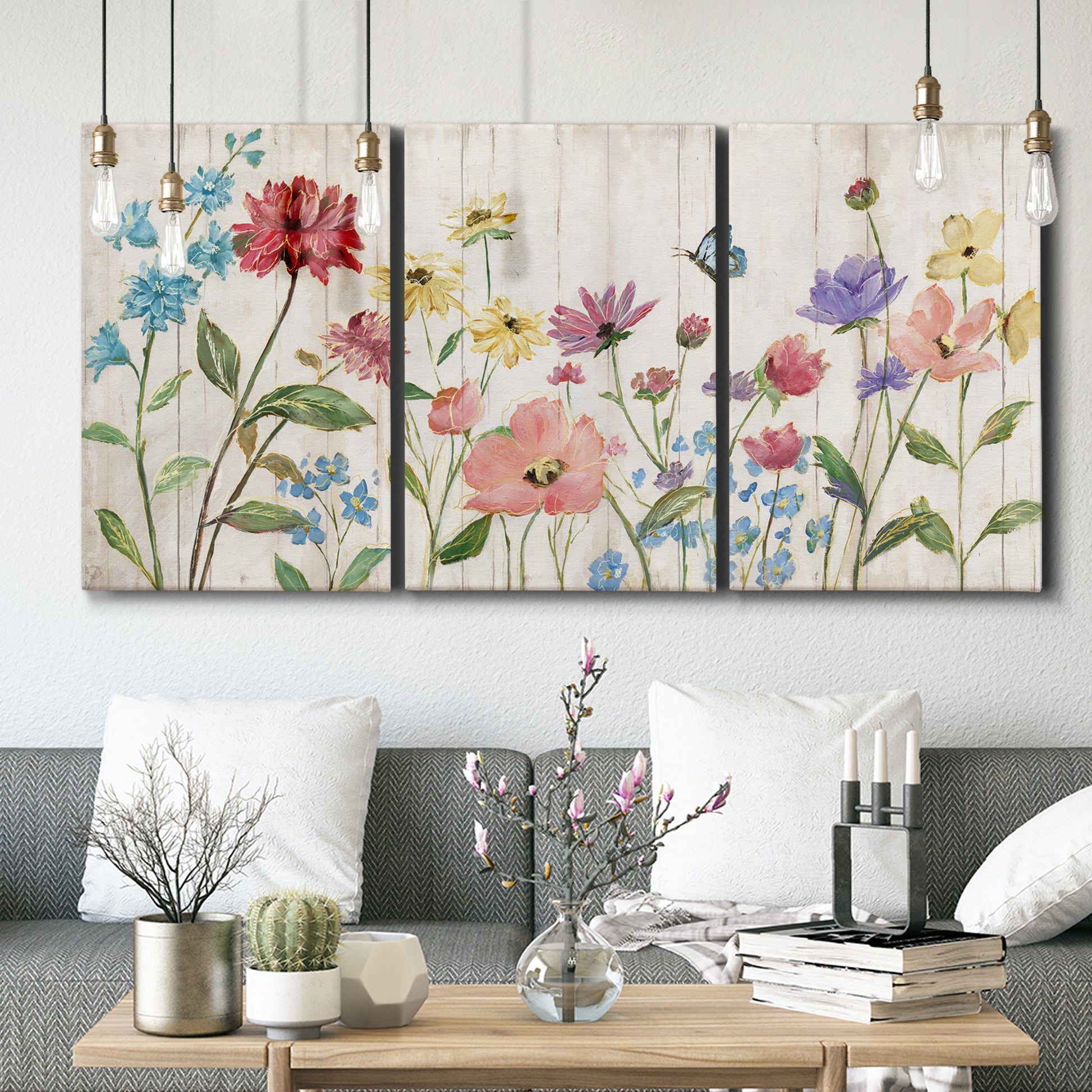 Three-panel canvas wall art featuring delicate wildflower illustration, displayed in a modern living room above seating.
