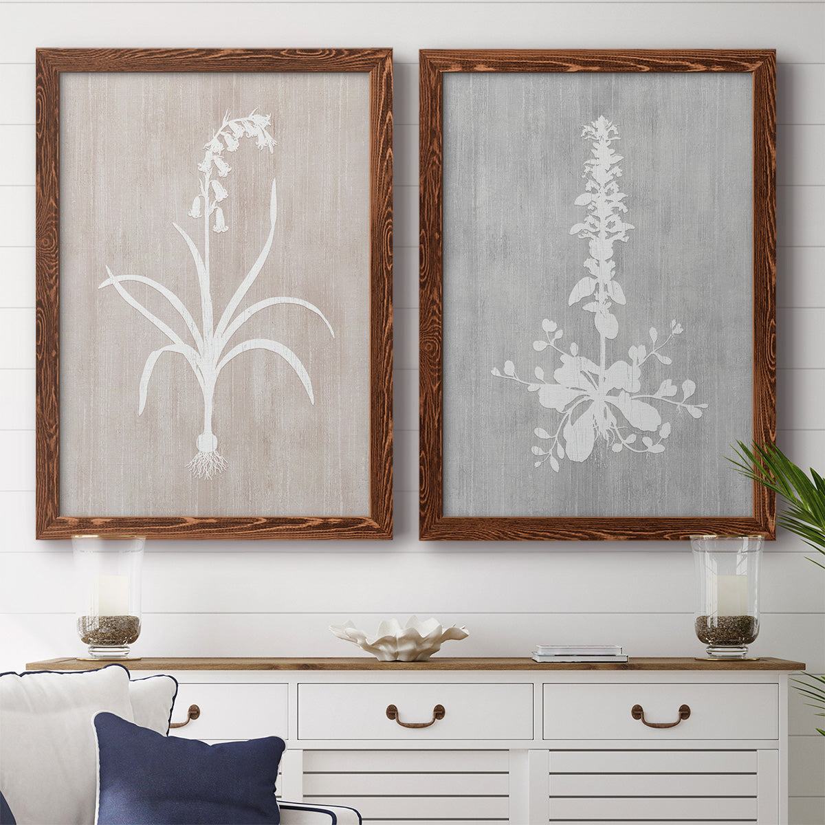 Set of two maple barnwood framed canvas prints depicting a coordinated art pair of white botanical silhouettes on softly weathered neutral backgrounds rendered as rustic minimalist botanical prints above a dining room sideboard.