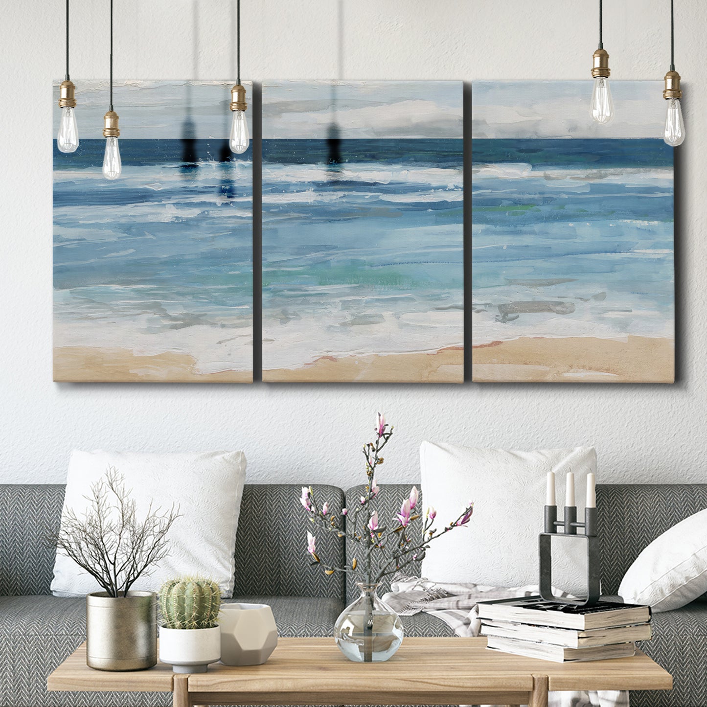 Three-panel canvas wall art featuring rolling ocean waves near shore, displayed in a modern living room above seating.