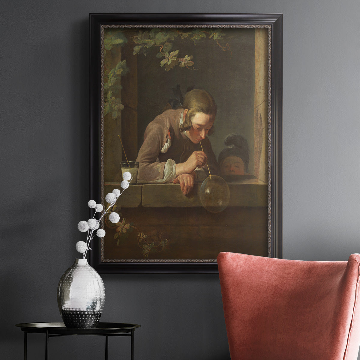 Classical genre painting of a child blowing soap bubbles by Jean-Siméon Chardin in an ornate black frame with gilded inner detail displayed in a dark-toned interior setting.