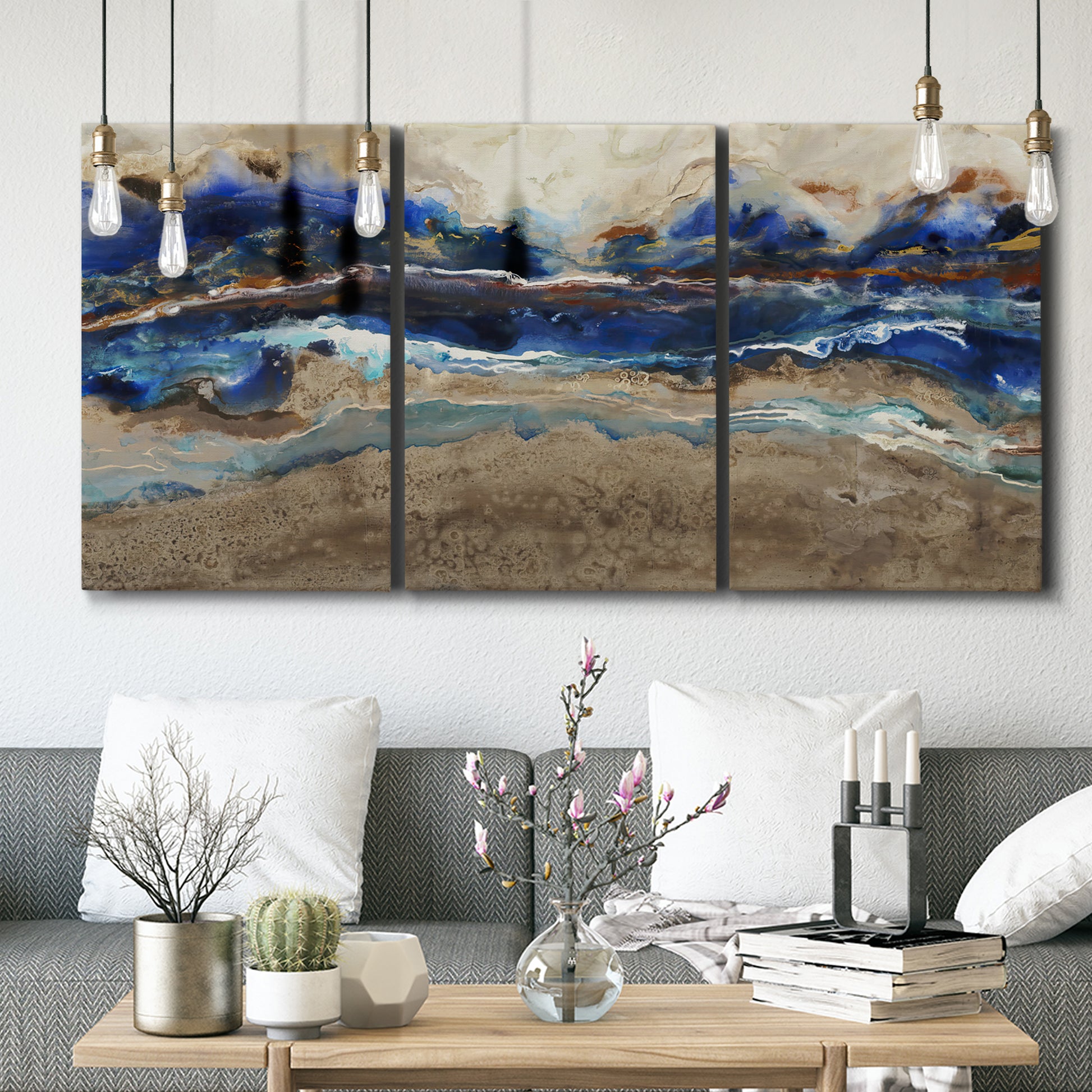 Three-panel canvas wall art featuring abstract coastal jewel toned composition, displayed in a modern living room above seating.