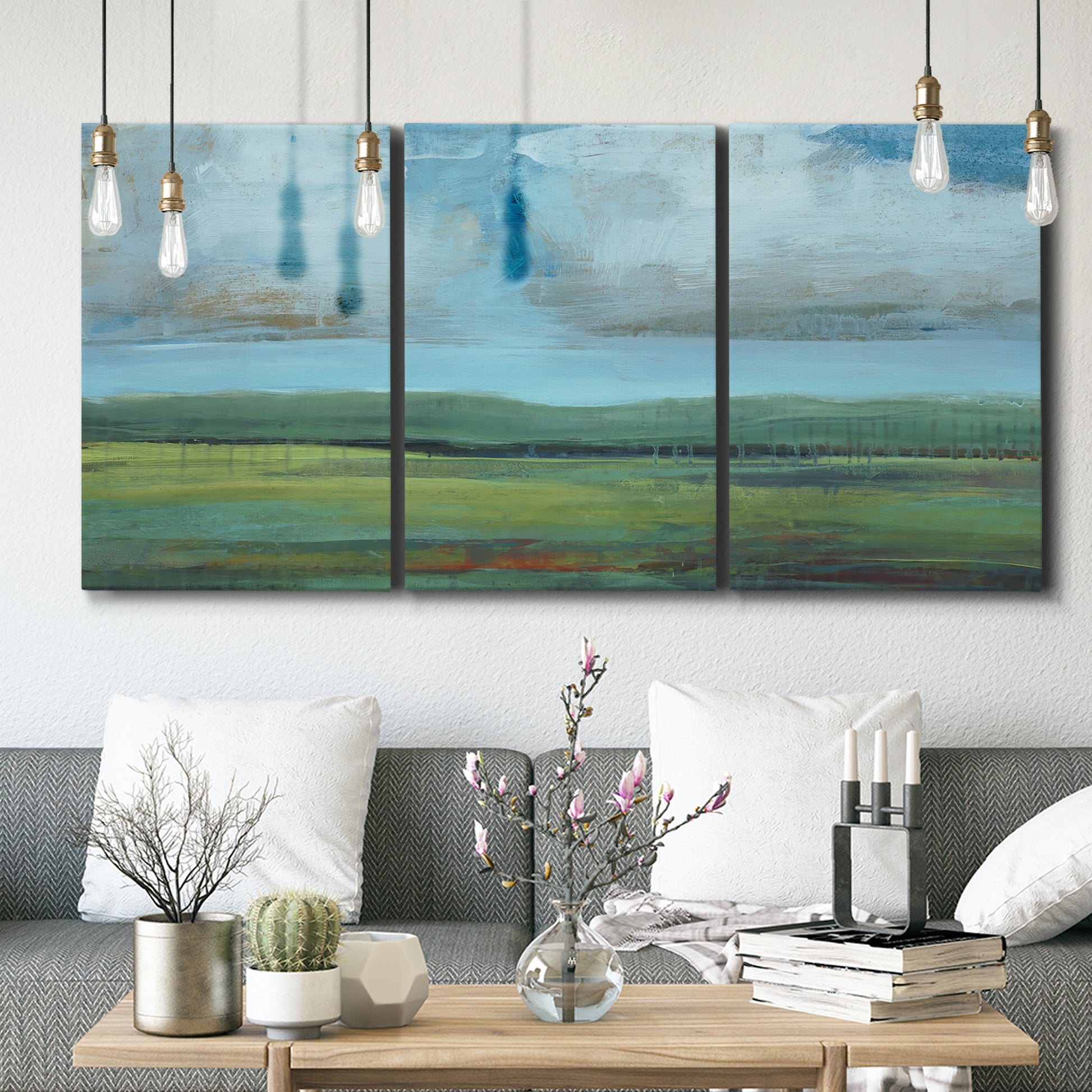 Three-panel canvas wall art featuring wide valley landscape with rolling hills, displayed in a modern living room above seating.