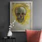Expressive skull study painting by Vincent van Gogh in an ornate champagne frame displayed in a dark-toned interior setting.