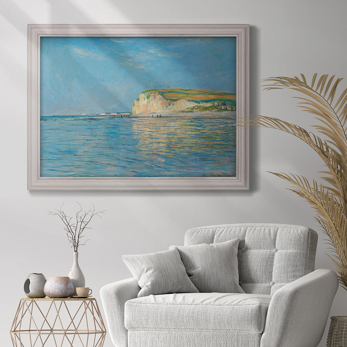 Impressionist coastal low-tide seascape at Pourville by Claude Monet in an ornate weathered white frame displayed in a bright interior setting.