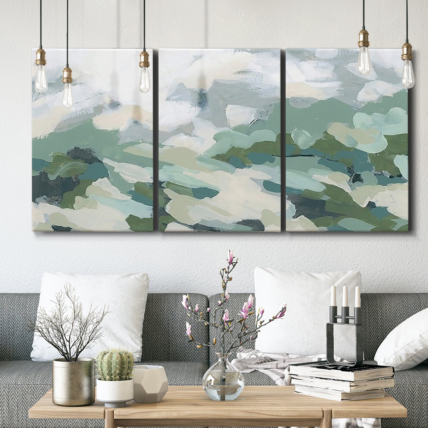 Three-panel canvas wall art featuring lush green hillside rolling landscape, displayed in a modern living room above seating.