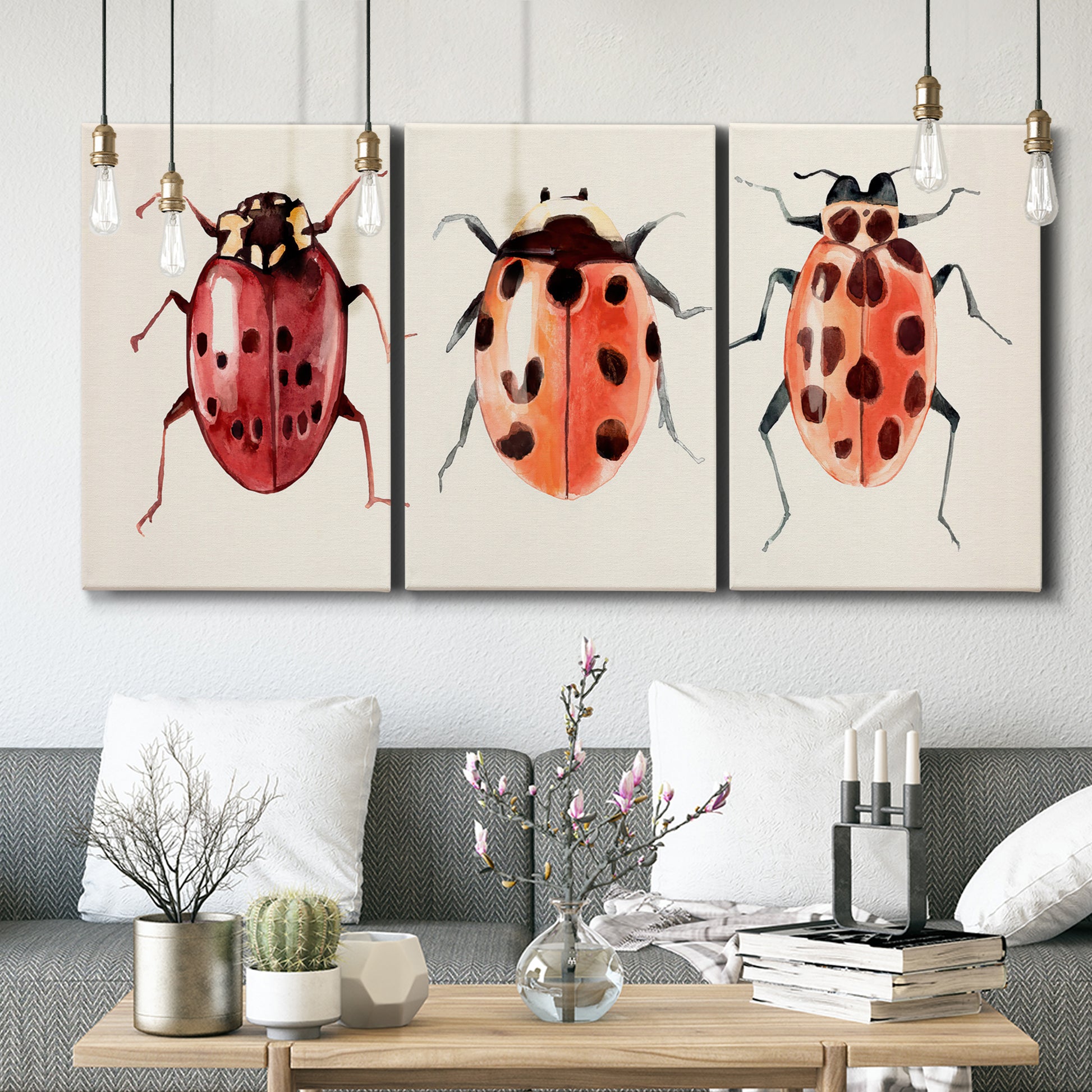 Three-panel canvas wall art featuring ladybugs on green foliage, displayed in a modern living room above seating.