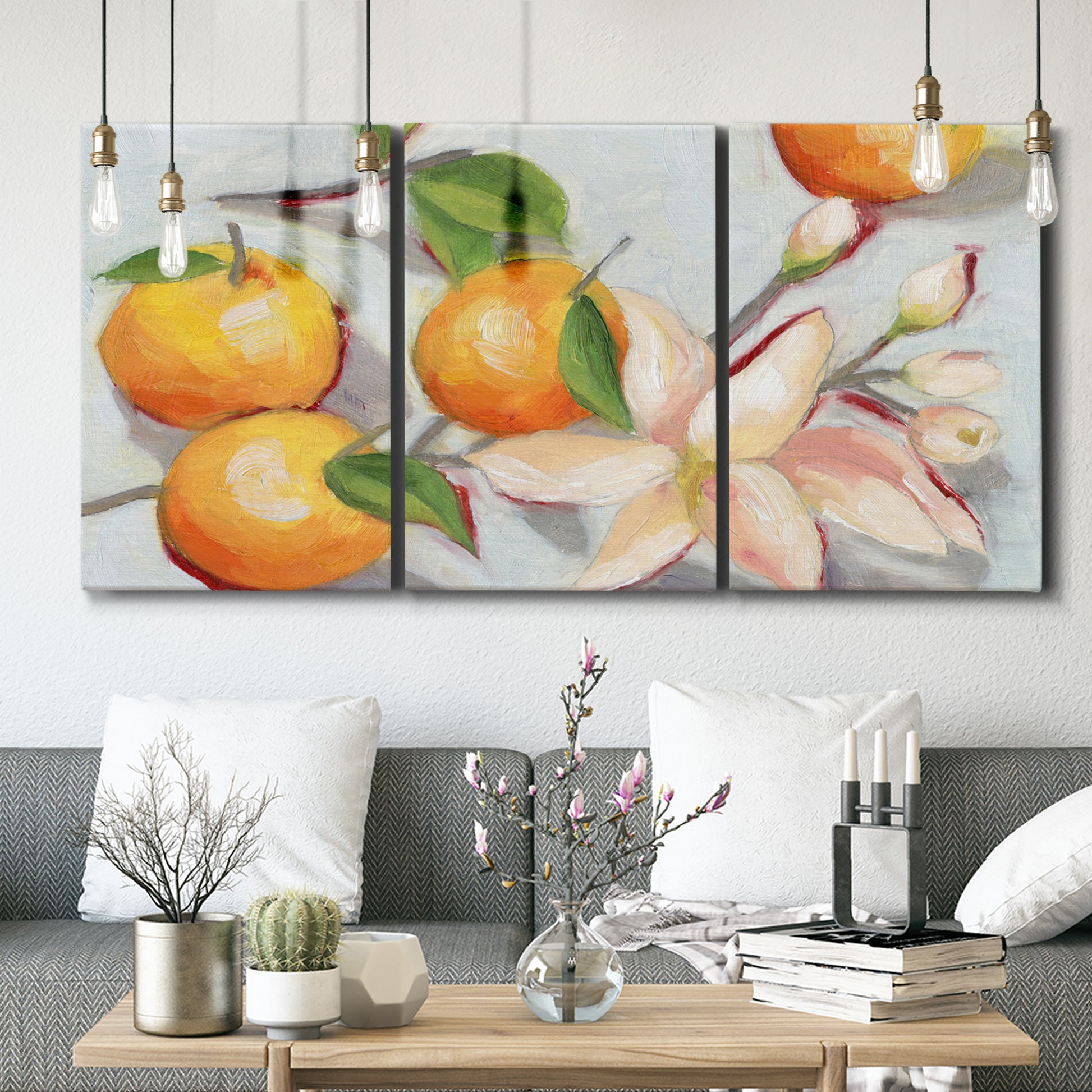 Three-panel canvas wall art featuring bright tangerine still life blossoms, displayed in a modern living room above seating.
