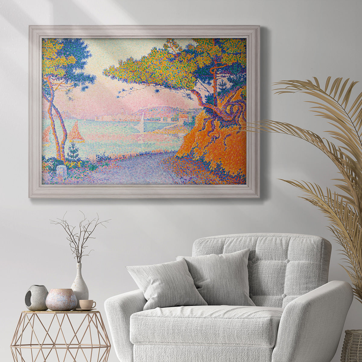 Pointillist coastal seascape by Paul Signac in an ornate weathered white frame displayed in a bright interior setting.