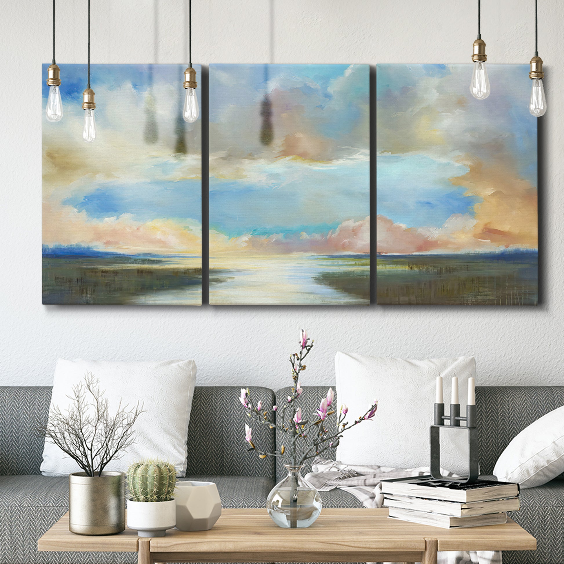 Three-panel canvas wall art featuring dawn light breaking over water, displayed in a modern living room above seating.