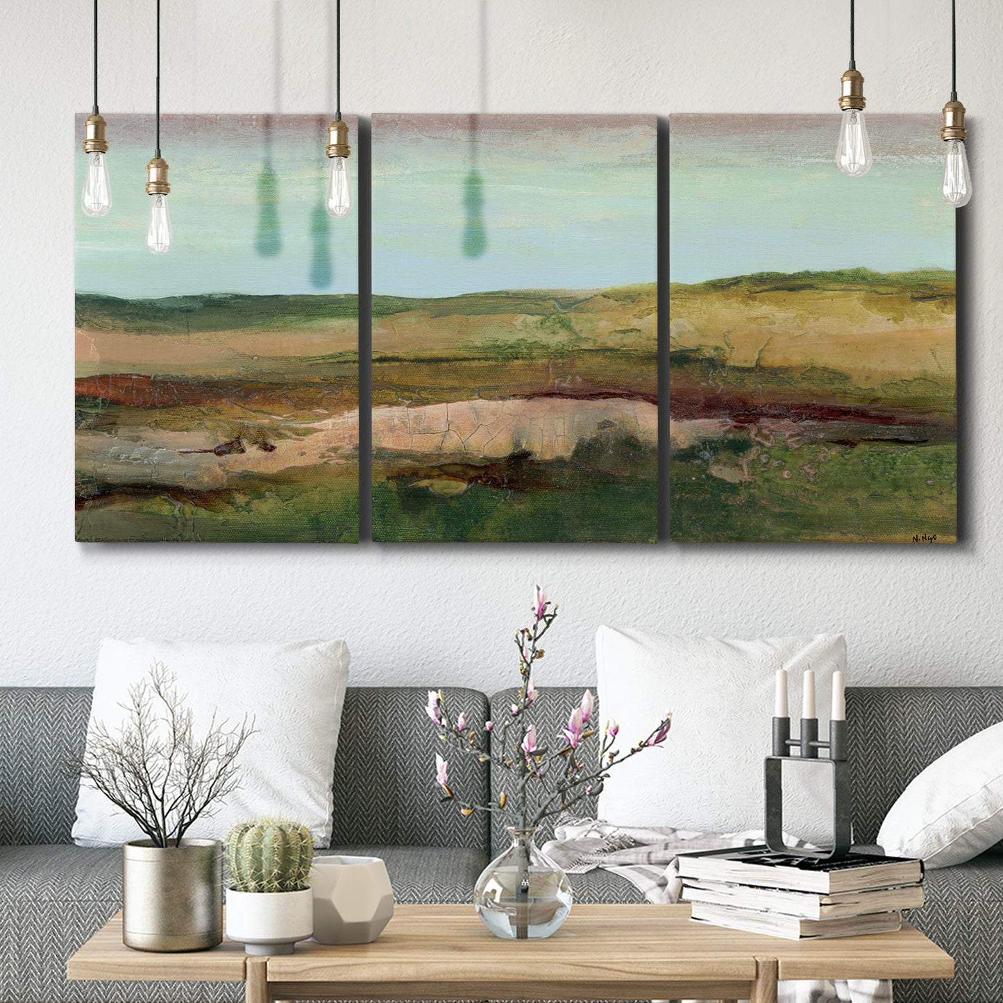 Three-panel canvas wall art featuring pastoral landscape with winding road, displayed in a modern living room above seating.