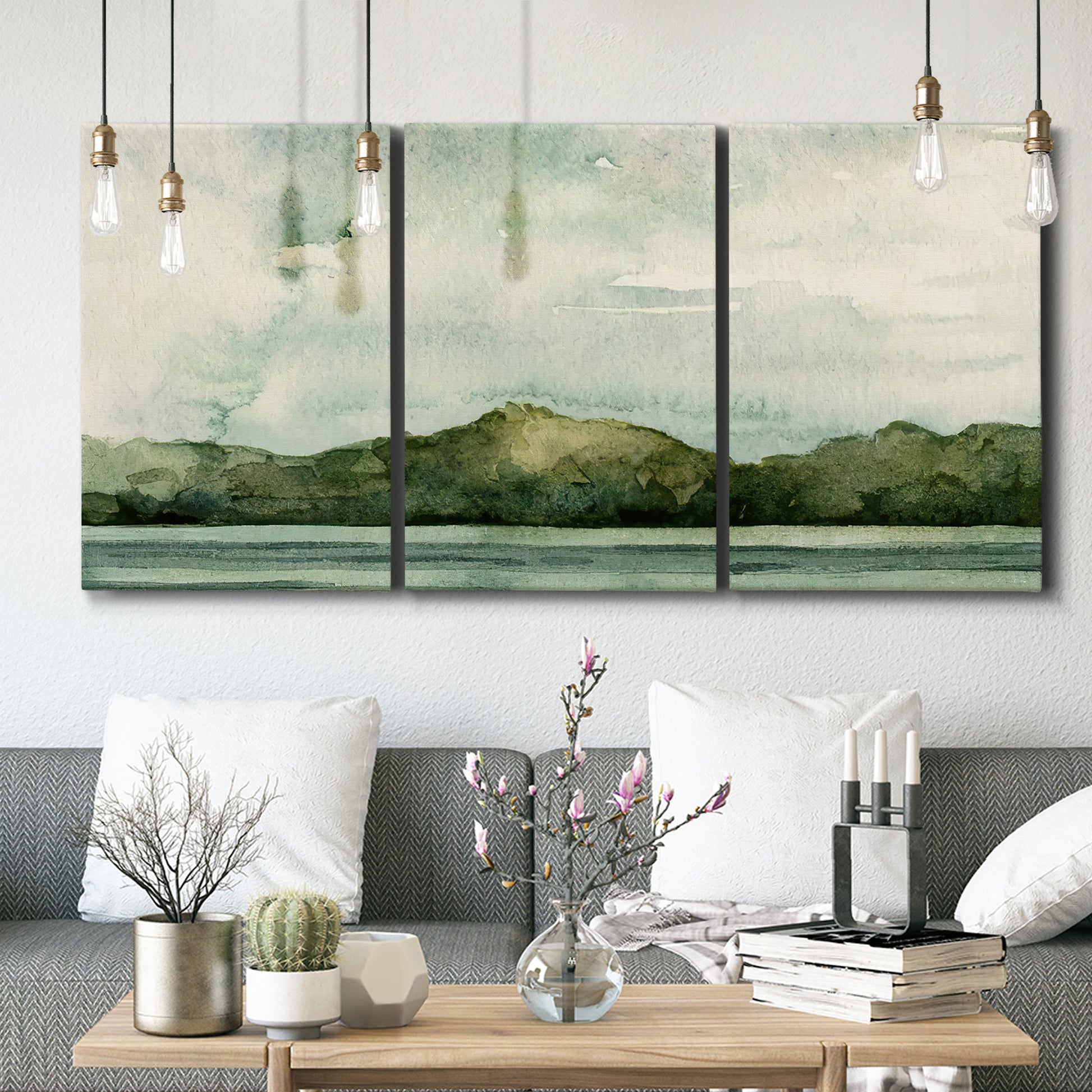 Three-panel canvas wall art featuring riverbank watercolor landscape, displayed in a modern living room above seating.
