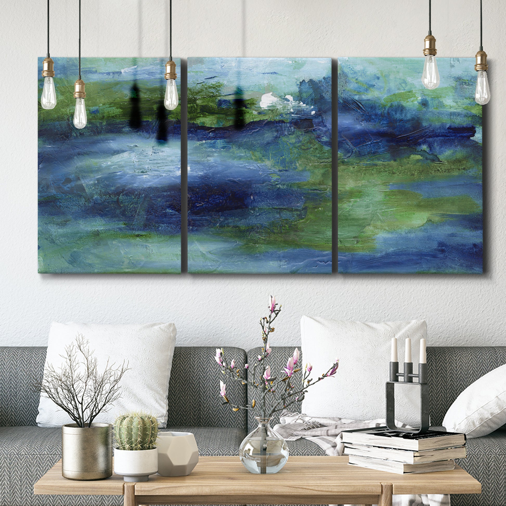 Three-panel canvas wall art featuring flowing blue abstract watercolor, displayed in a modern living room above seating.