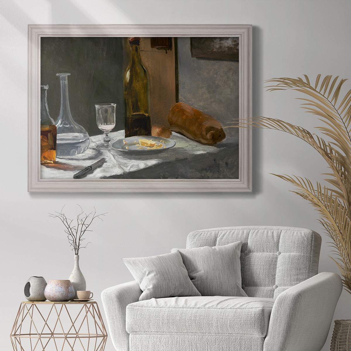 Impressionist still life with wine and bread by Claude Monet in an ornate weathered white frame displayed in a bright interior setting.