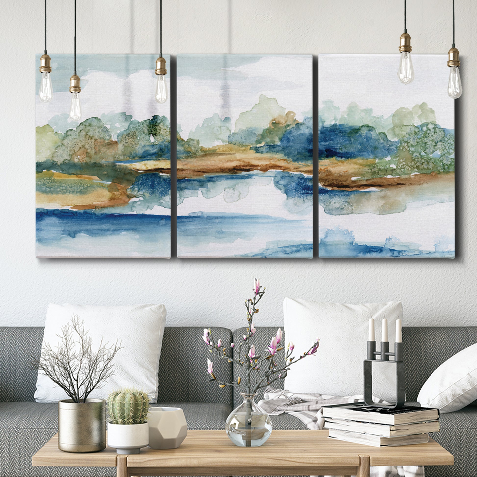 Three-panel canvas wall art featuring abstract blue watercolor landscape, displayed in a modern living room above seating.