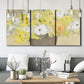 Three-panel canvas wall art featuring abstract floral table arrangement, displayed in a modern living room above seating.