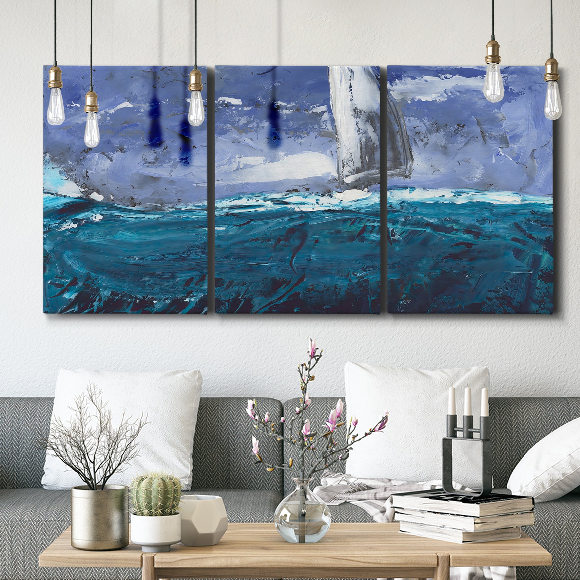 Three-panel canvas wall art featuring sailboats moving across water, displayed in a modern living room above seating.