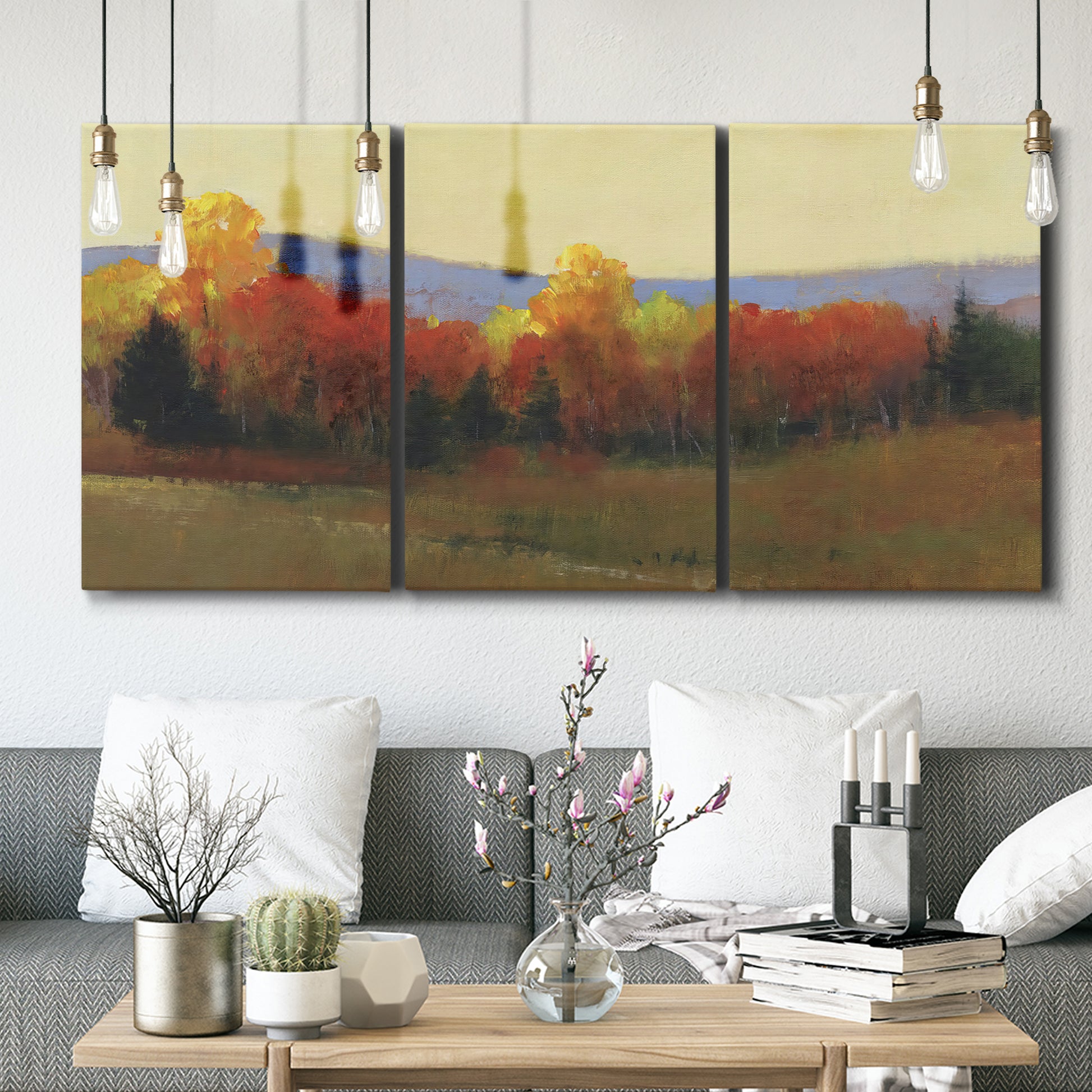 Three-panel canvas wall art featuring autumn landscape changing foliage, displayed in a modern living room above seating.