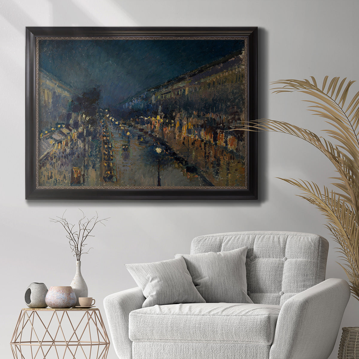 Impressionist nighttime Paris street scene by Camille Pissarro in an ornate black frame with gilded inner detail displayed in a bright interior setting.