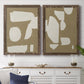 Set of two walnut barnwood framed canvas prints depicting a coordinated art pair of irregular white cutout-like shapes on taupe grounds rendered as bold minimalist shape abstracts above a dining room sideboard.