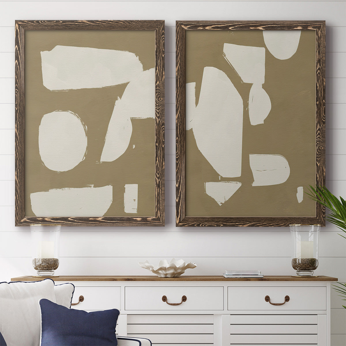Set of two walnut barnwood framed canvas prints depicting a coordinated art pair of irregular white cutout-like shapes on taupe grounds rendered as bold minimalist shape abstracts above a dining room sideboard.