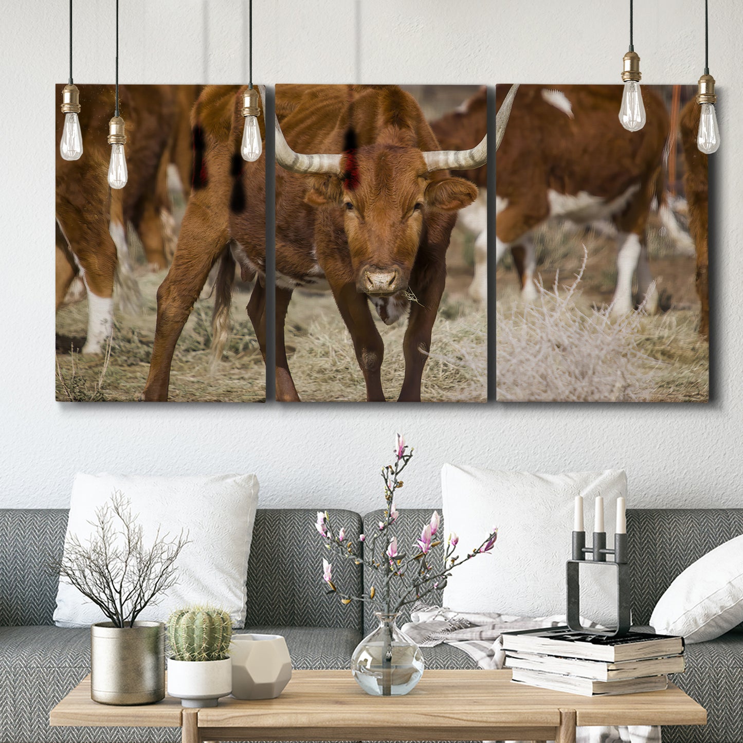 Three-panel canvas wall art featuring longhorn cattle standing together, displayed in a modern living room above seating.