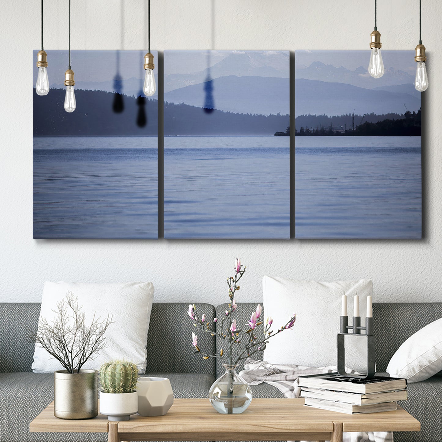 Three-panel canvas wall art featuring calm blue water landscape, displayed in a modern living room above seating.