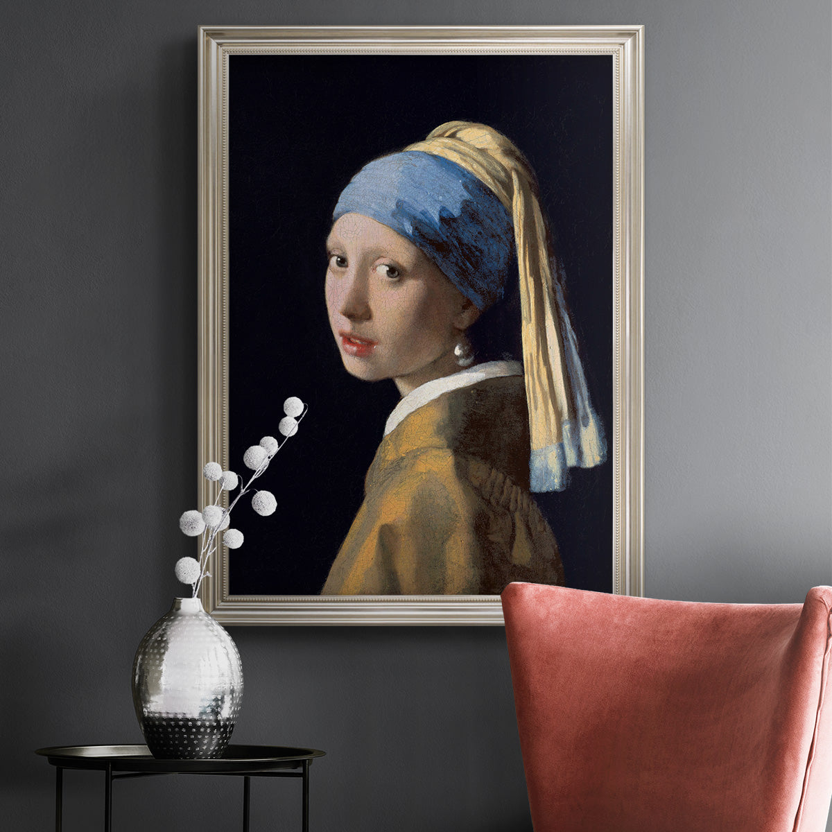 Iconic portrait of a girl wearing a pearl earring by Johannes Vermeer in an ornate champagne frame displayed in a dark-toned interior setting.