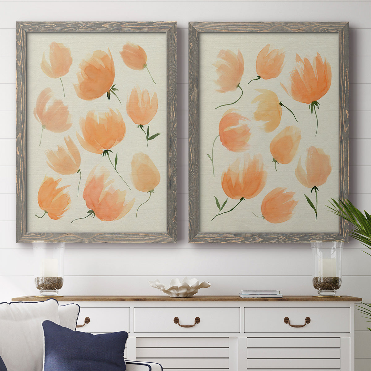 Set of two gray barnwood framed canvas prints depicting a coordinated art pair of loose peach-orange tulip-like blossoms rendered as airy watercolor floral paintings above a dining room sideboard.