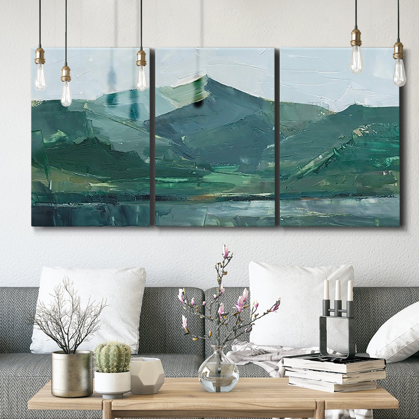 Three-panel canvas wall art featuring muted mountain range in grey tones, displayed in a modern living room above seating.