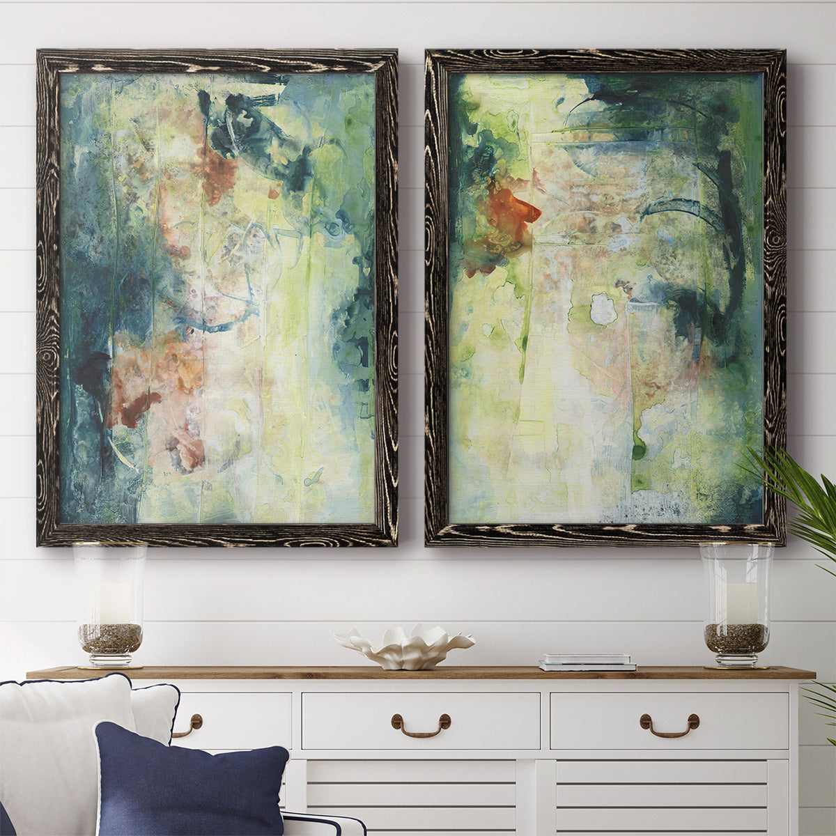 Set of two black barnwood framed canvas prints depicting a coordinated art pair of layered blue green cream and charcoal textures rendered as nature-inspired mixed-media abstracts above a dining room sideboard.