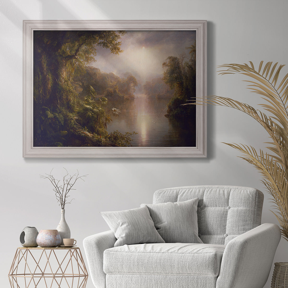 Luminous romantic landscape painting by Frederic Edwin Church in an ornate champagne frame displayed in a bright interior setting.