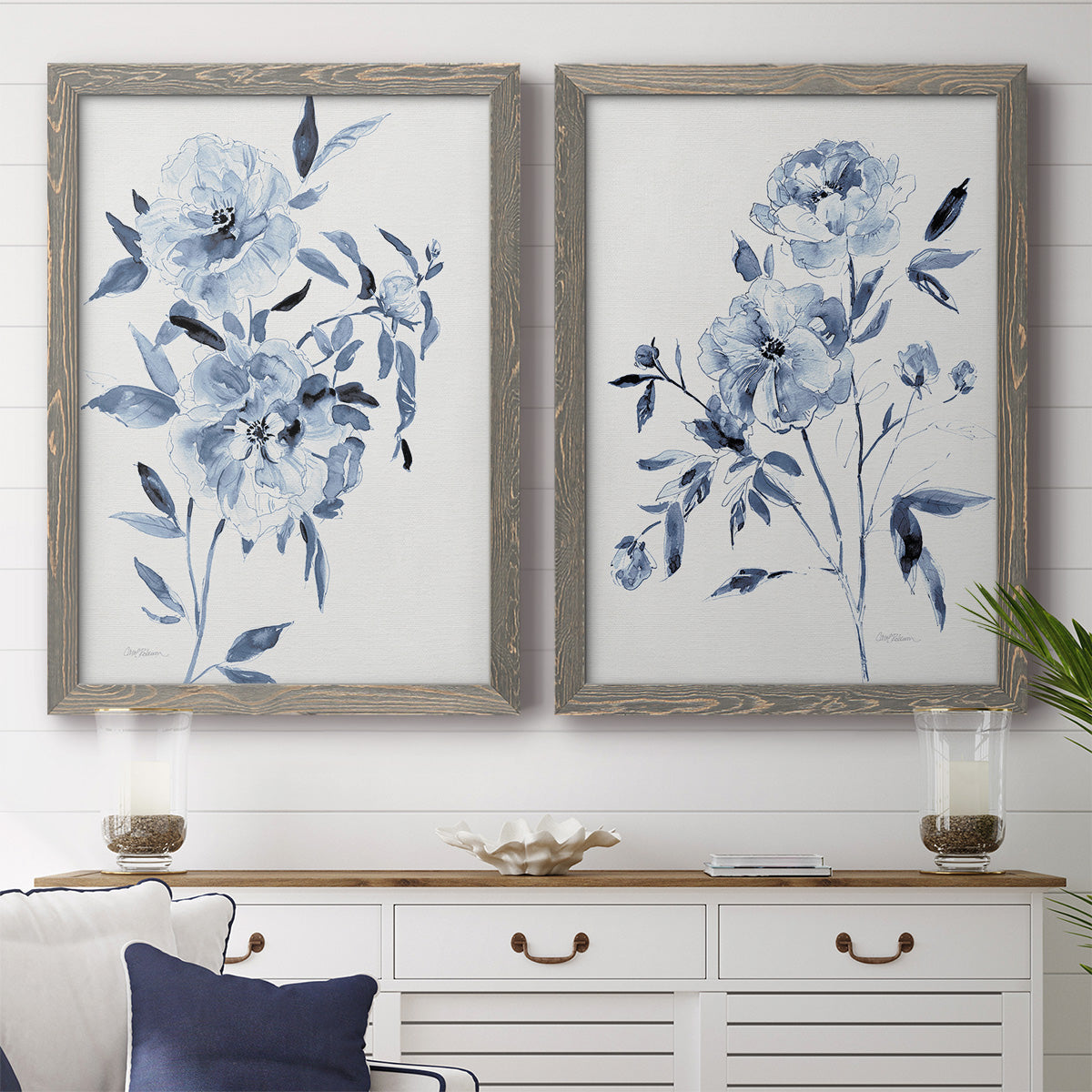 Set of two gray barnwood framed canvas prints depicting a coordinated art pair of loose blue flowers and leafy branches rendered as expressive watercolor botanical paintings above a dining room sideboard.