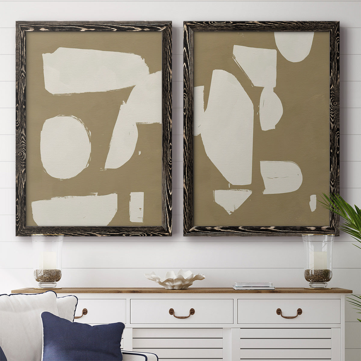 Set of two black barnwood framed canvas prints depicting a coordinated art pair of irregular white cutout-like shapes on taupe grounds rendered as bold minimalist shape abstracts above a dining room sideboard.