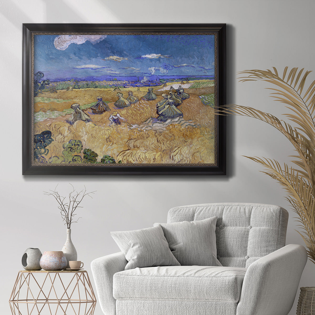 Impressionist wheat harvest scene by Vincent van Gogh in an ornate black frame with gilded inner detail displayed in a bright interior setting.