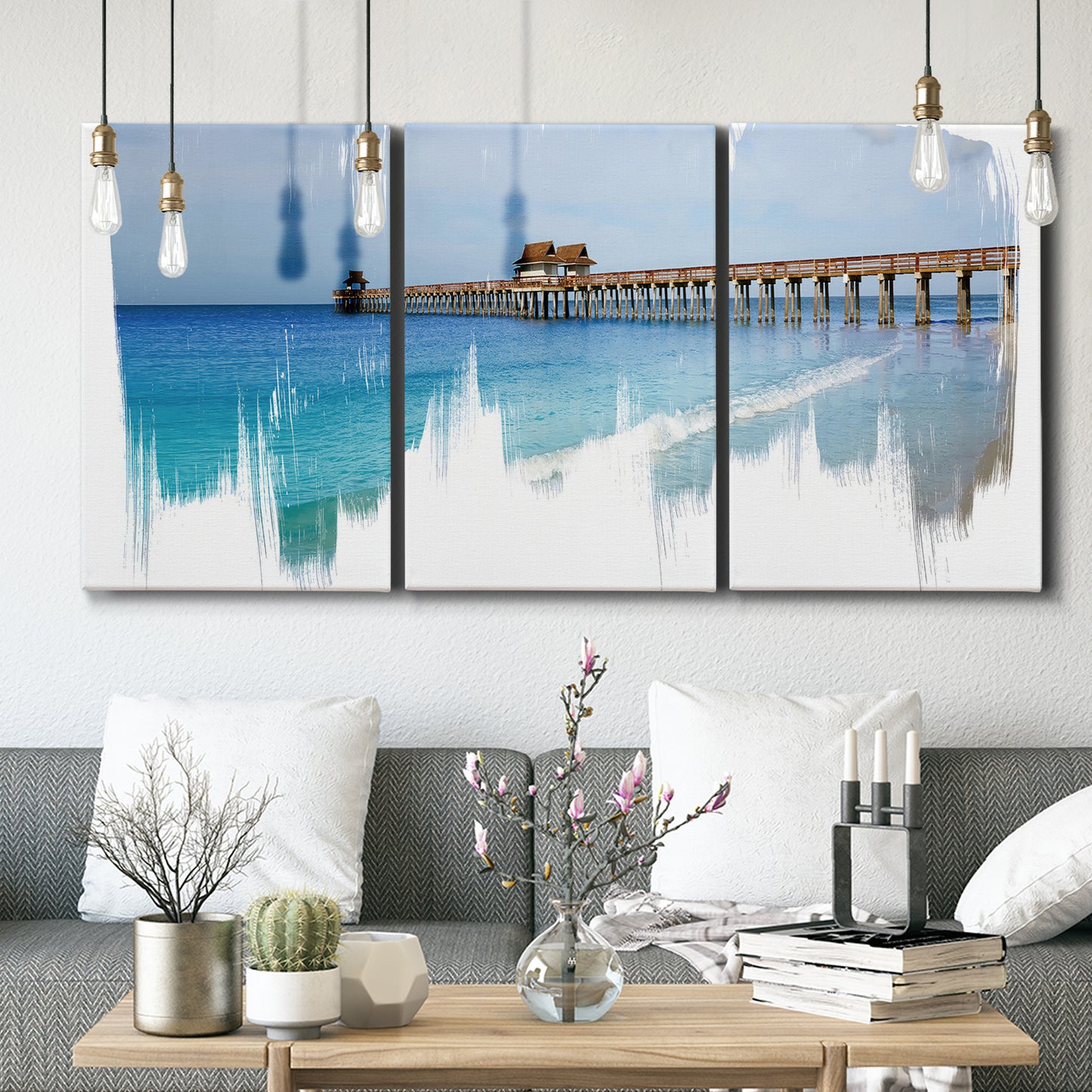 Three-panel canvas wall art featuring coastal pier extending over water, displayed in a modern living room above seating.