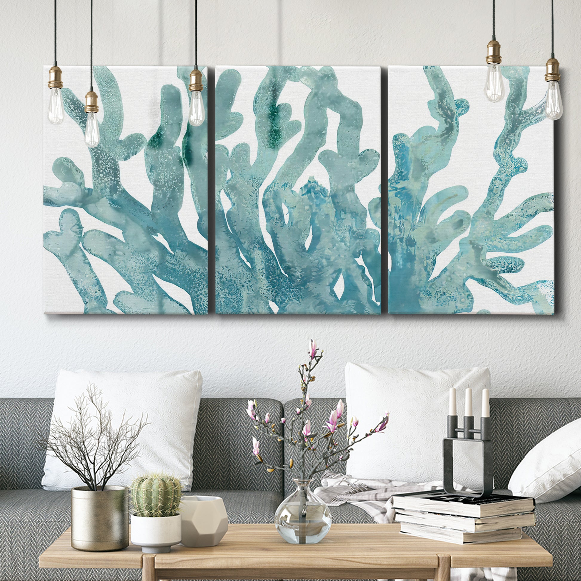 Three-panel canvas wall art featuring blue coral inspired watercolor, displayed in a modern living room above seating.