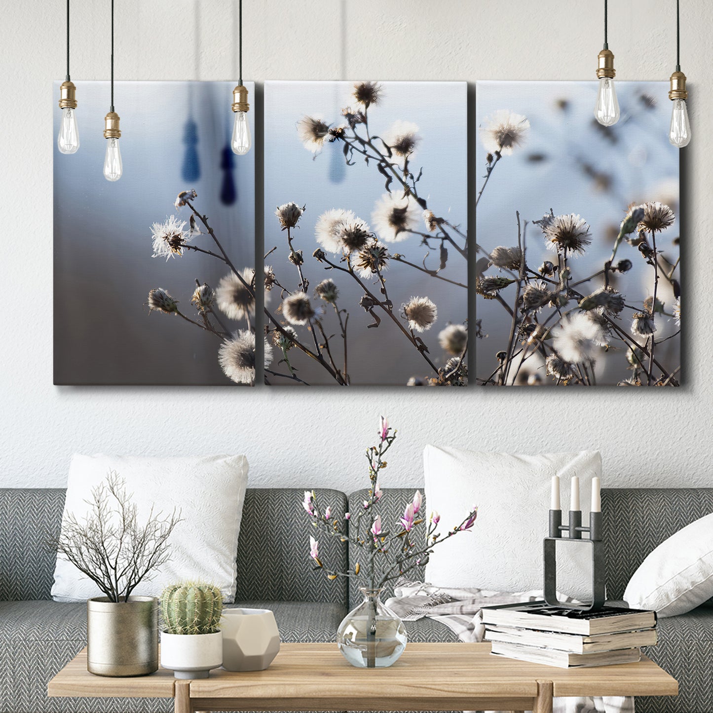 Three-panel canvas wall art featuring delicate spring blossoms on branches, displayed in a modern living room above seating.