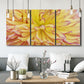 Three-panel canvas wall art featuring close up floral blossoms in bloom, displayed in a modern living room above seating.