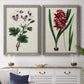 Set of two gray barnwood framed canvas prints depicting a coordinated art pair of colorful flowering plant specimens rendered as antique botanical plate illustrations above a dining room sideboard.