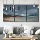 Three-panel canvas wall art featuring stormy sea glass toned coastline, displayed in a modern living room above seating.