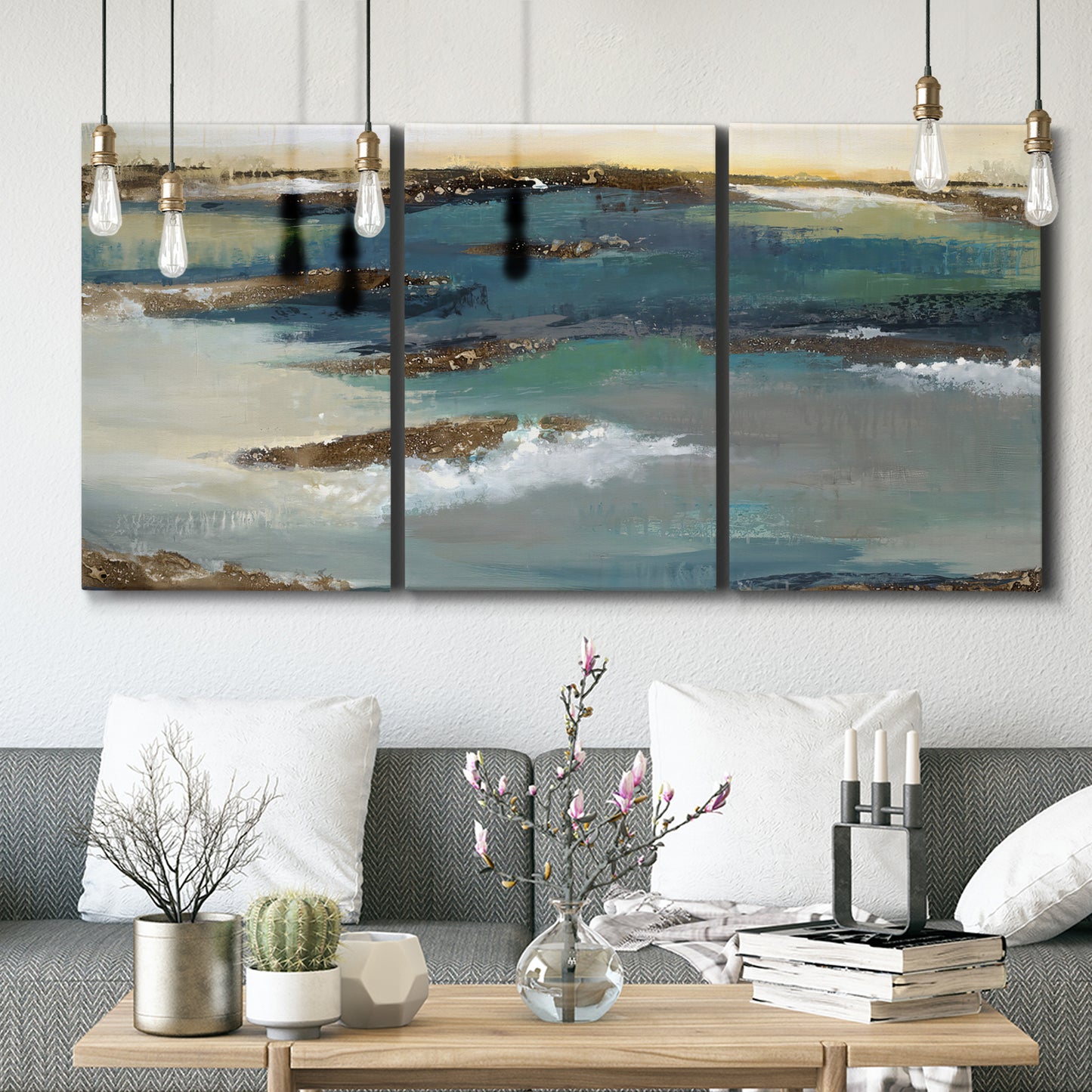 Three-panel canvas wall art featuring rocky coastal bluff above sea, displayed in a modern living room above seating.
