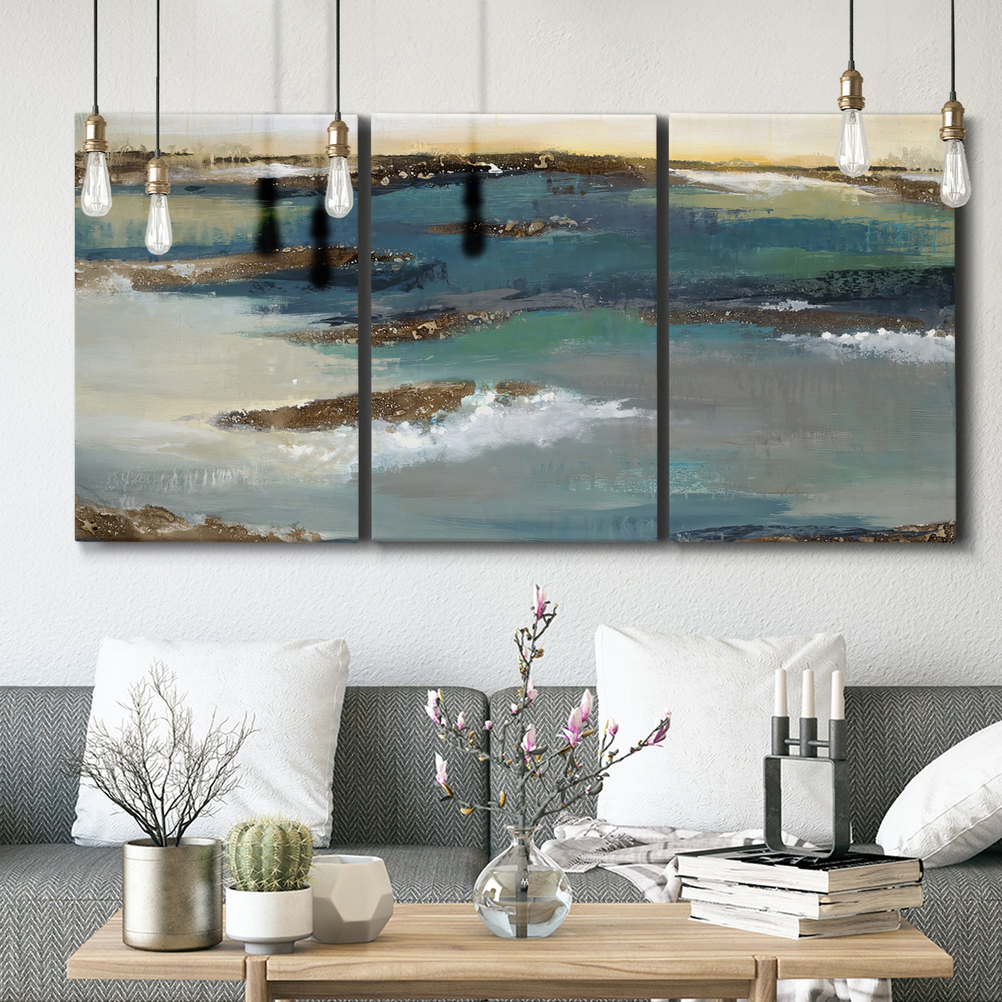 Three-panel canvas wall art featuring rocky coastal bluff above sea, displayed in a modern living room above seating.