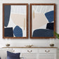 Set of two maple barnwood framed canvas prints depicting a coordinated art pair of large navy cream and beige organic geometric shapes rendered as minimalist color-block abstracts above a dining room sideboard.
