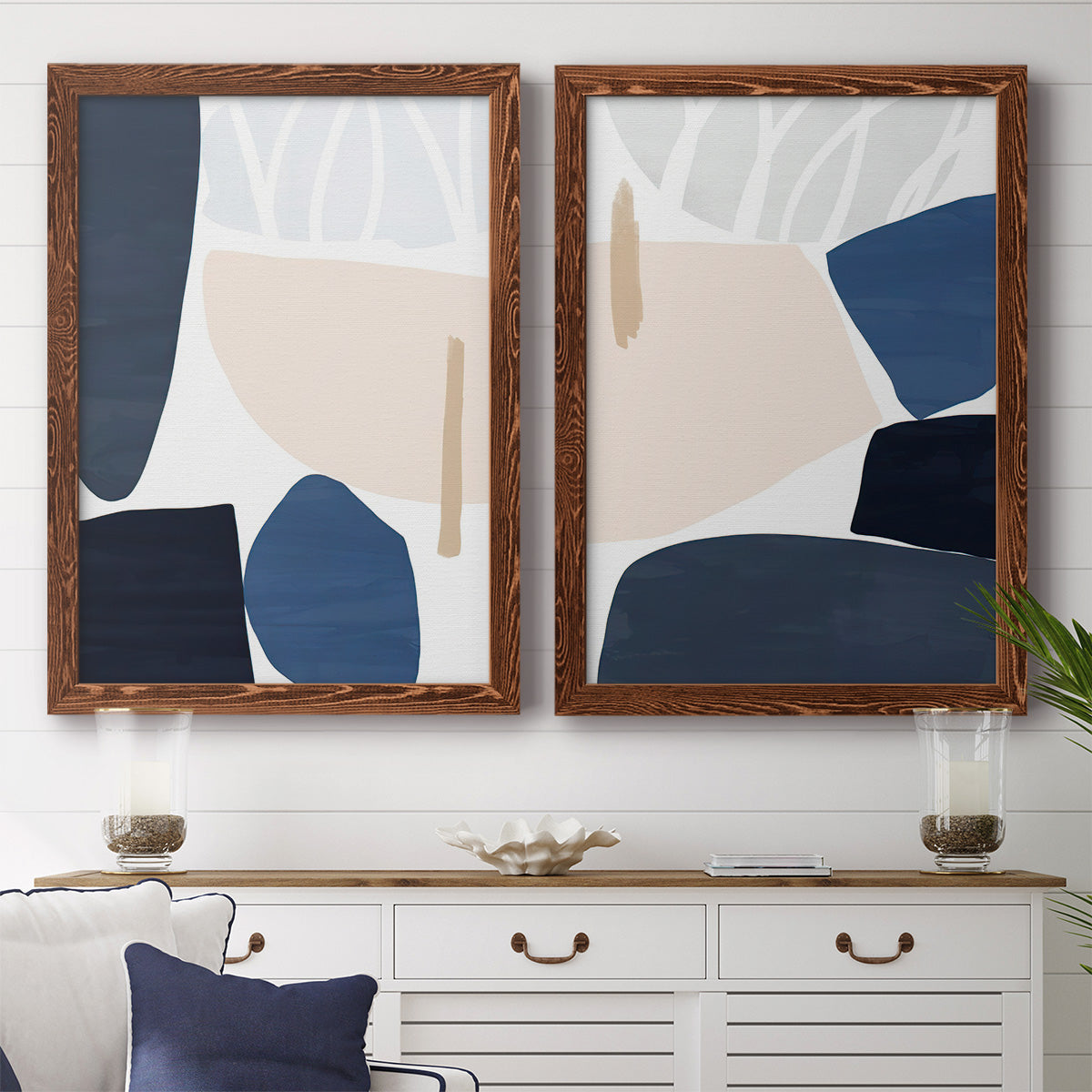 Set of two maple barnwood framed canvas prints depicting a coordinated art pair of large navy cream and beige organic geometric shapes rendered as minimalist color-block abstracts above a dining room sideboard.