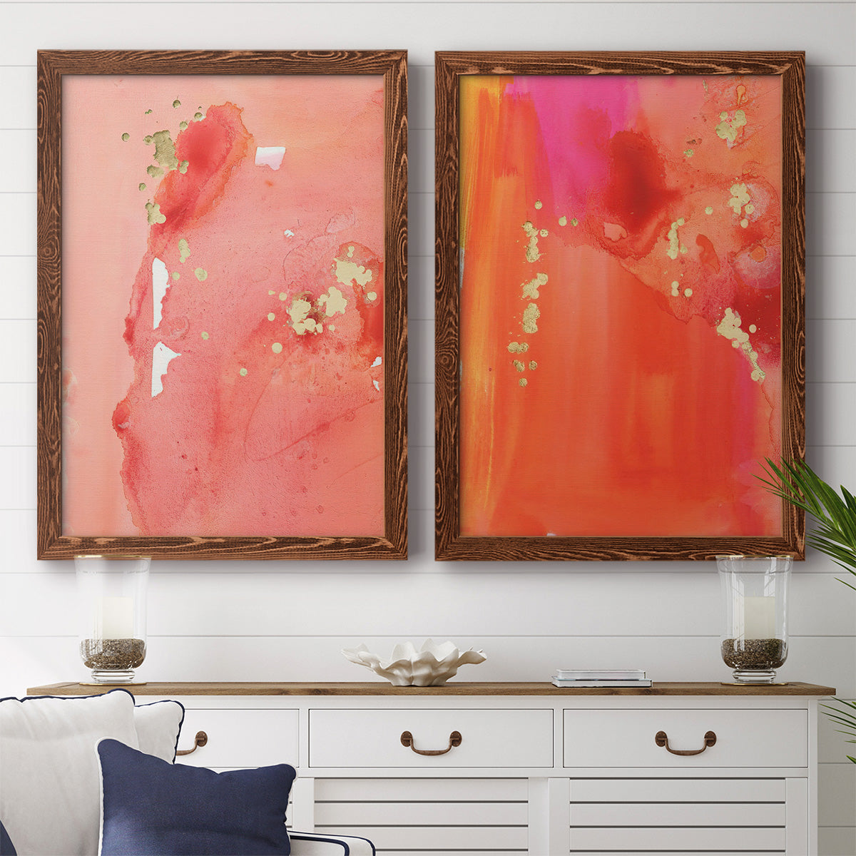 Set of two maple barnwood framed canvas prints depicting a coordinated art pair of luminous coral orange and pink color fields with gold flecks rendered as glamorous fluid abstracts above a dining room sideboard.