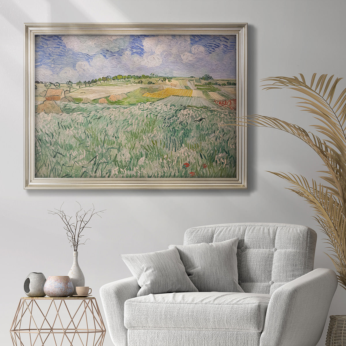 Impressionist countryside landscape near Auvers by Vincent van Gogh in an ornate champagne frame displayed in a bright interior setting.