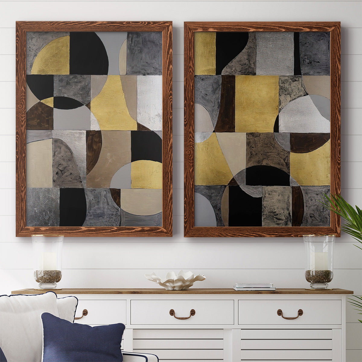 Set of two maple barnwood framed canvas prints depicting a coordinated art pair of interlocking black gray cream and gold geometric sections rendered as structured modern abstracts above a dining room sideboard.